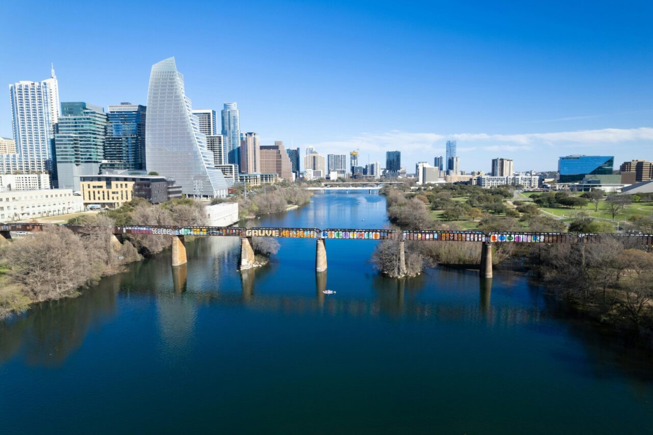 Stunning aerial view of Austin, Texas skyline featuring a graffiti-covered bridge over the river.