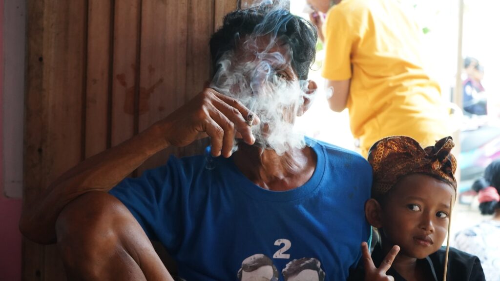 A man smoking a cigarette next to a little girl