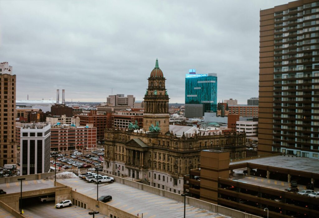 Aerial view of Detroit city showcasing historic and modern buildings under a cloudy sky.
