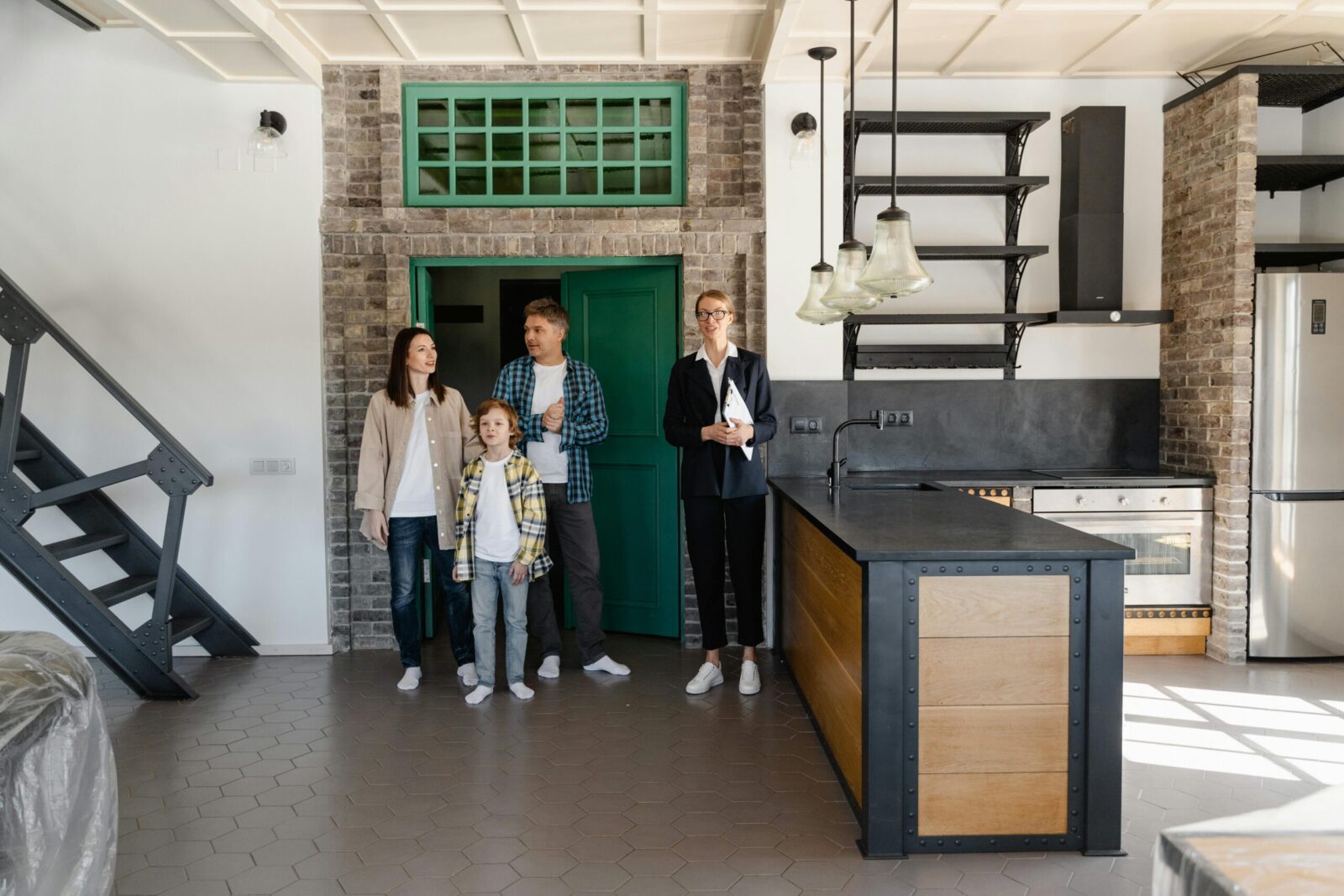 A family with a realtor viewing a modern industrial-style kitchen in a new home.